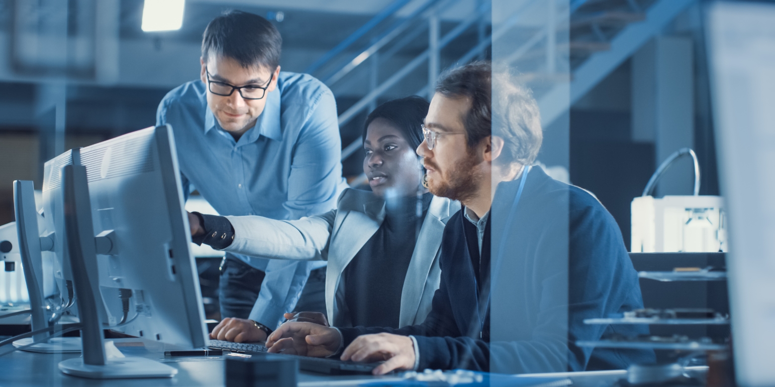 3 people around a computer in an office
